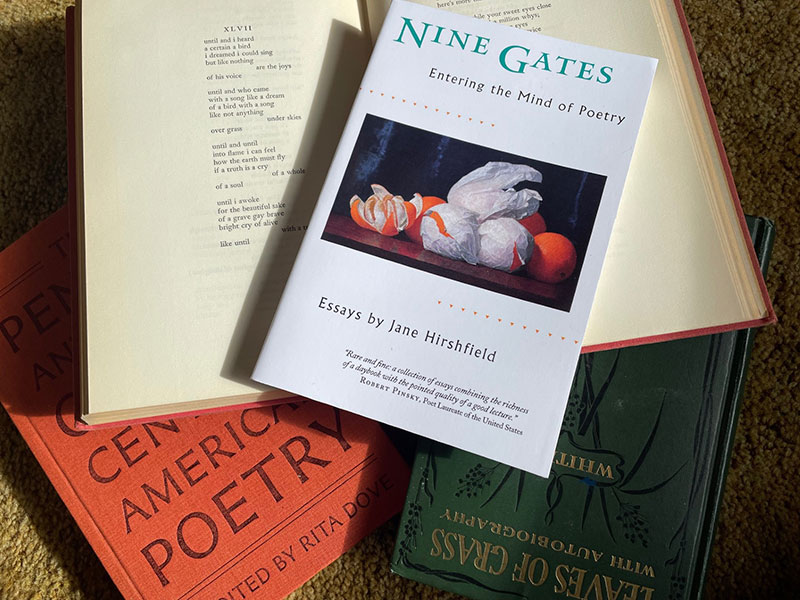 a stack of poetry books, one of which is open to a poem