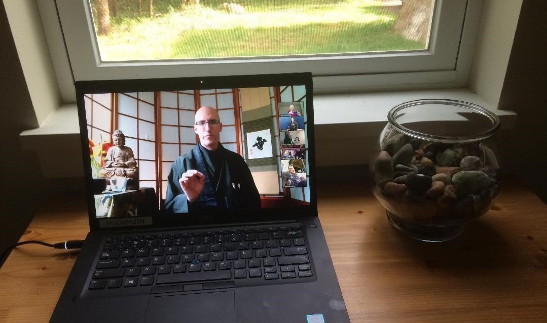 a computer in front of a window with Koshin on the screen giving a Zen teaching.