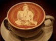 A cup of coffee with a Buddha image in the foam