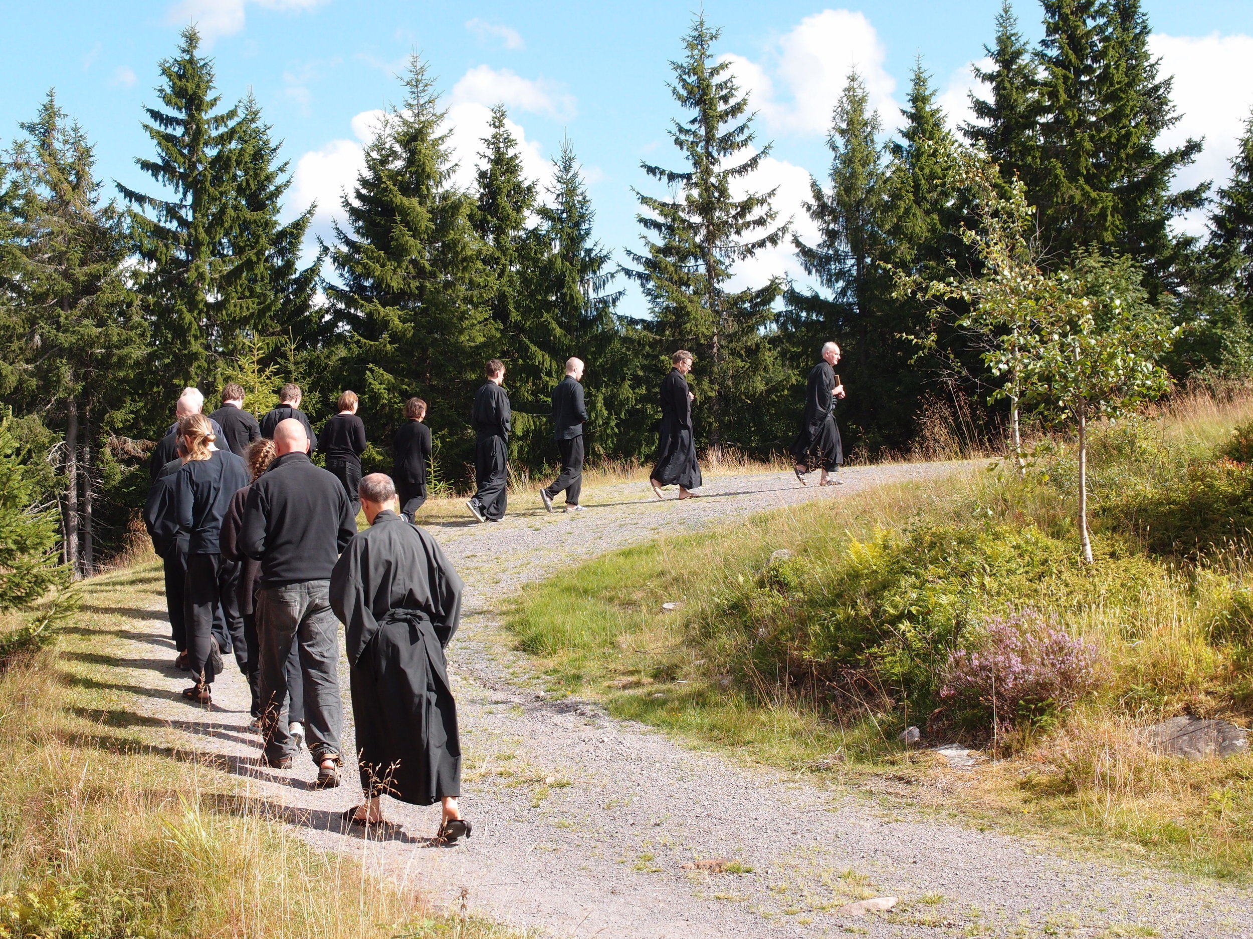 Oslo Rinzai Zen members wearing black robes and walking up a hill in Norway.