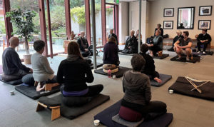 People sitting on meditation cushions listening to a dharma talk.