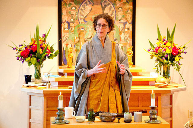 Anita Feng, in Buddhist robes, stands in front of some of her pottery.