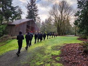 Retreat participants in single file walking meditation on green grass at Camp Sealth.