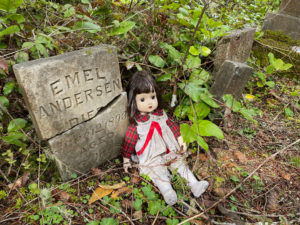 a child's tombstone with a doll placed next to it.